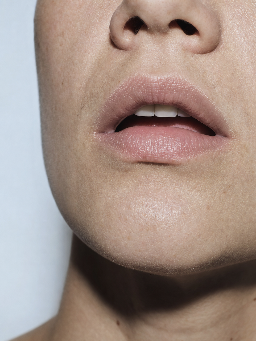 Campaign key art. Shot close and cold-flashed — a mouth mid-sentence, caught before the sentence lands.