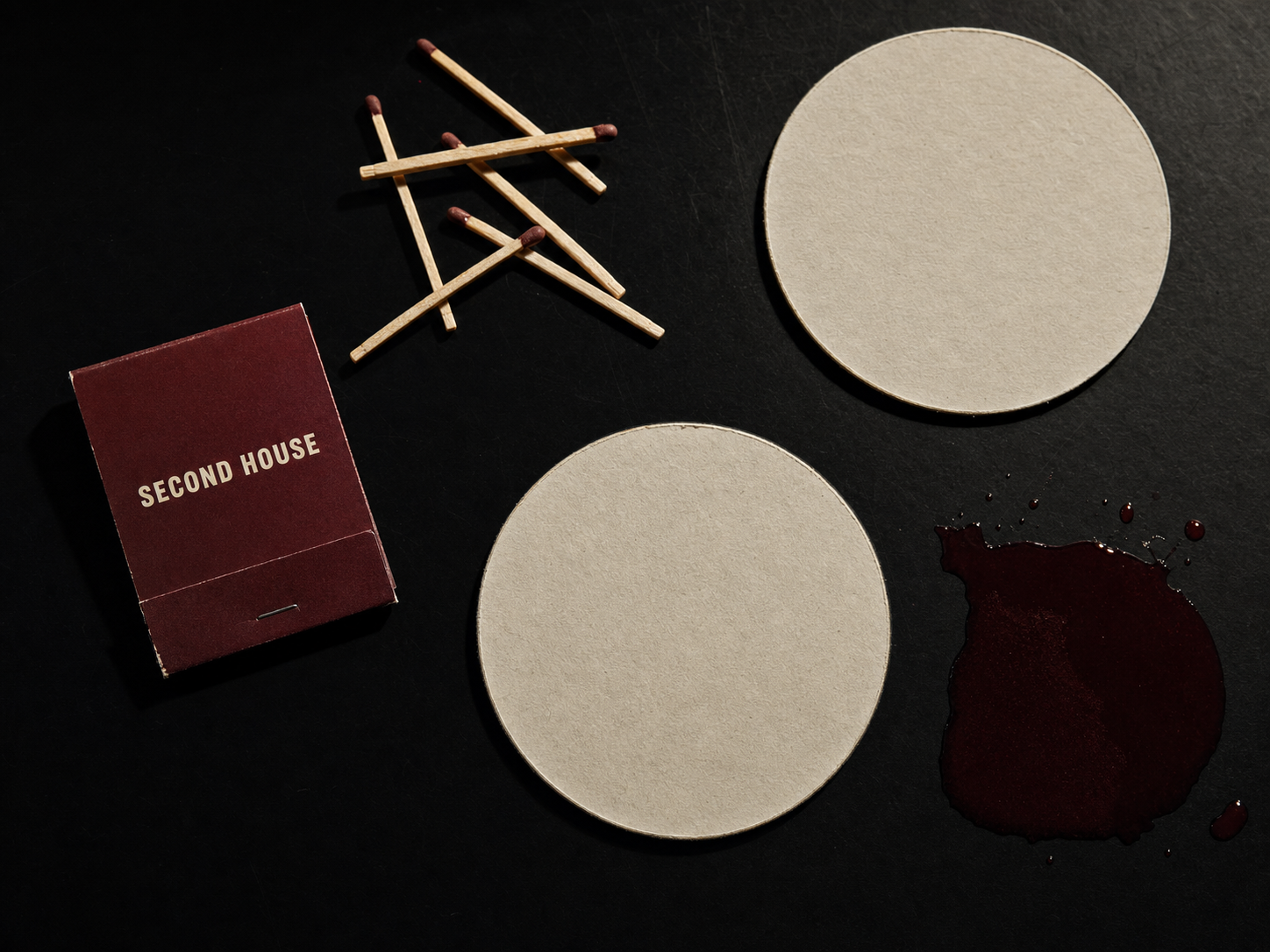 Matchbooks and coasters — the objects that leave with the guest and keep working afterwards.