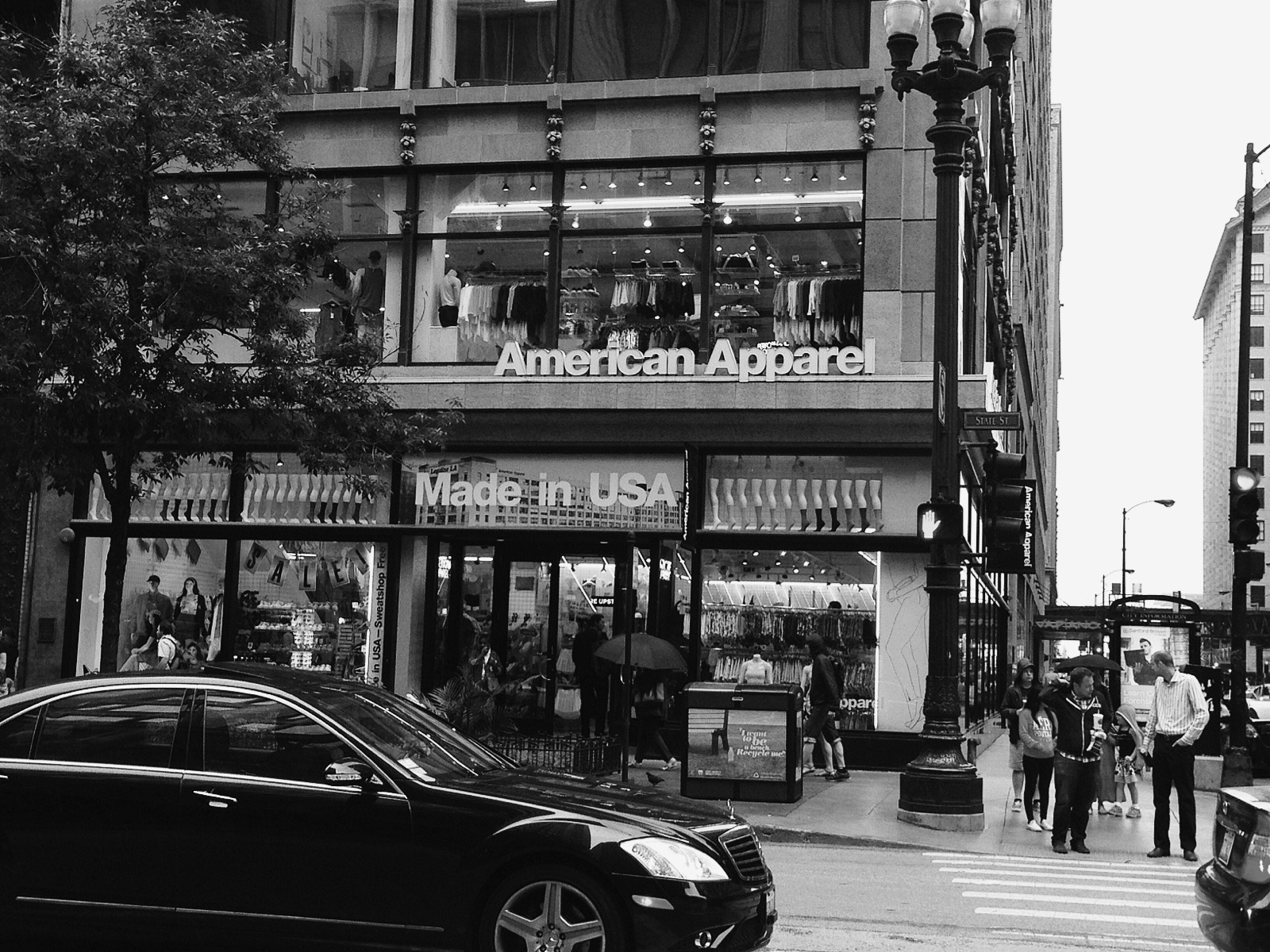 Black and white street scene with a car and urban storefronts