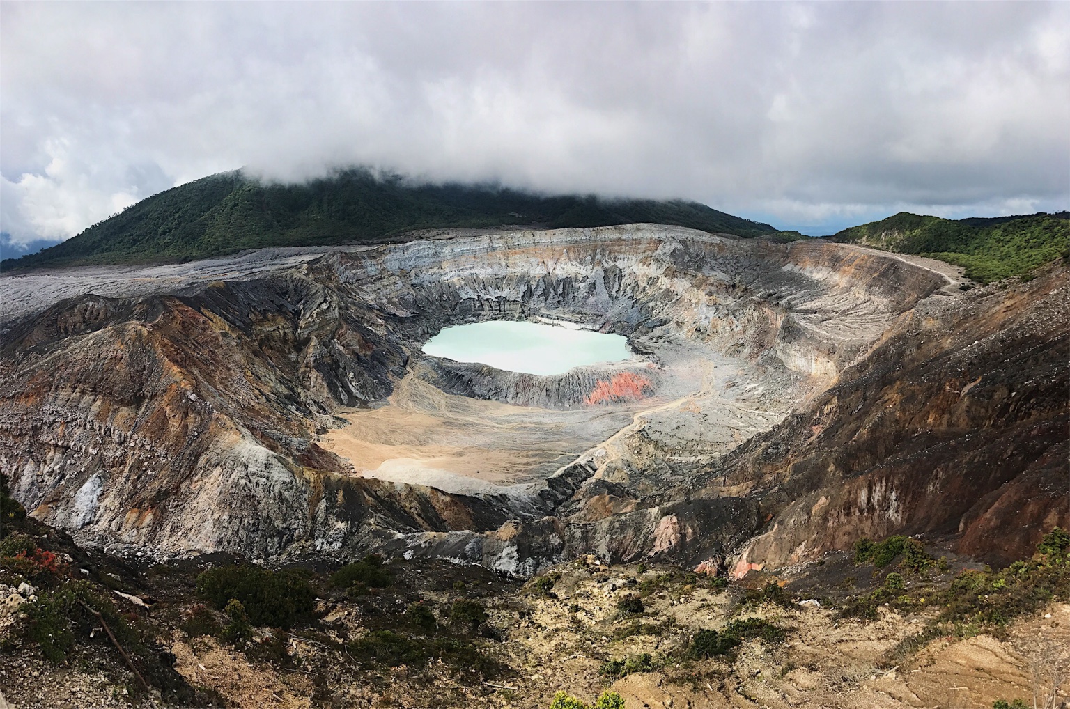 A volcanic crater with a pale lake framed by mountains