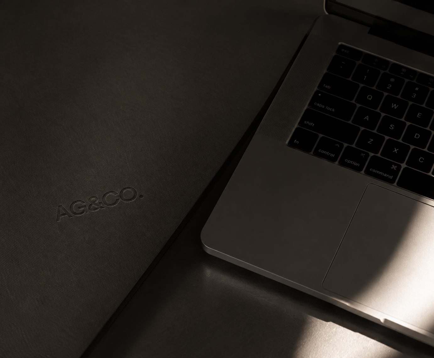 Open MacBook and embossed AG&CO. portfolio